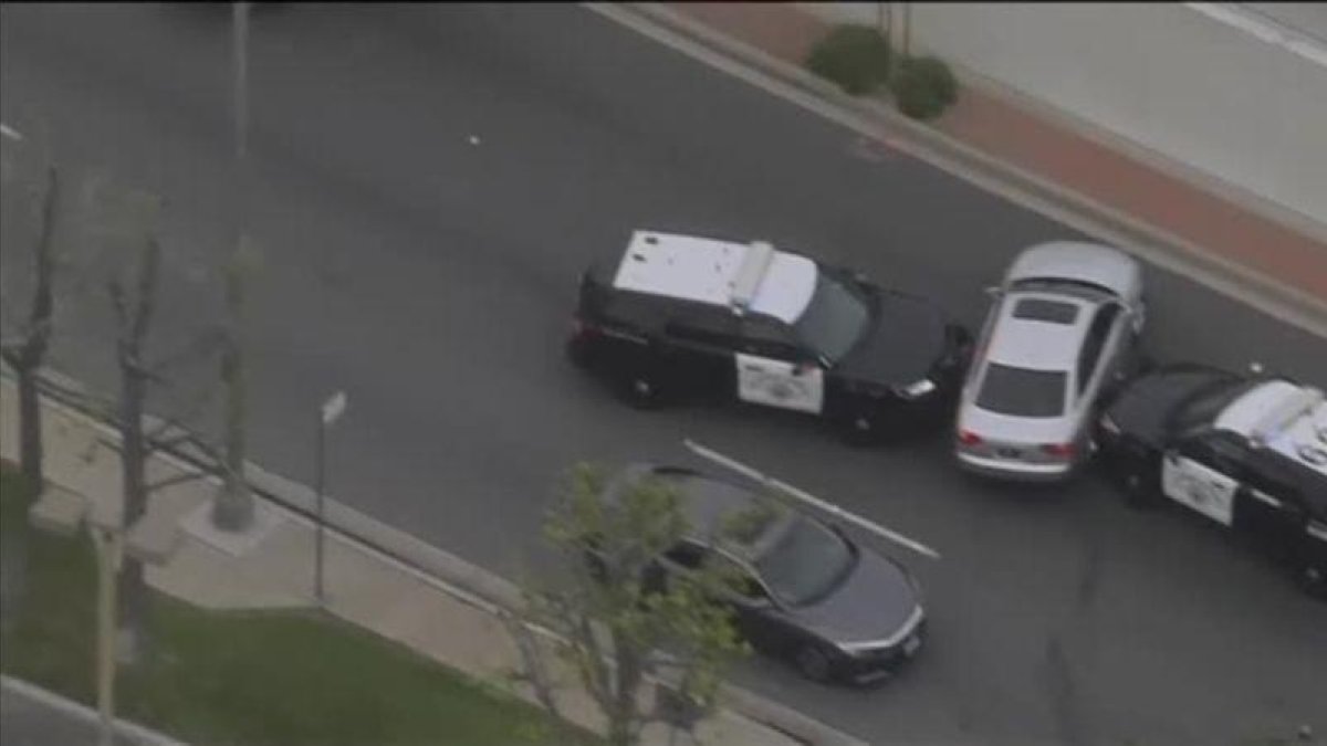 Parecía que dos coches de policía habían acorralado al ladrón de un vehículo cuando consigue escapar conduciendo de un lado a otro de la carretera.-EL PERIÓDICO