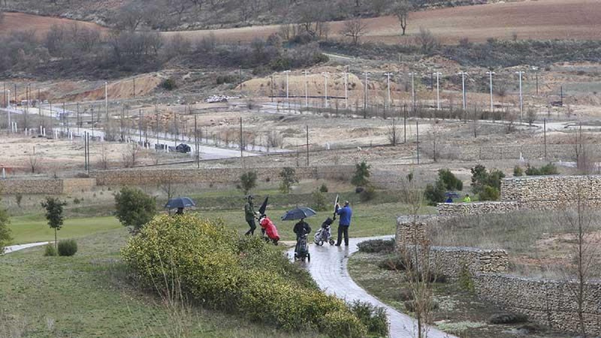 Varios jugadores realizan un recorrido por el Golf de Saldaña con las parcelas al fondo, urbanizadas y sin edificar de la urbanización en que se enclava.-RAÚL OCHOA