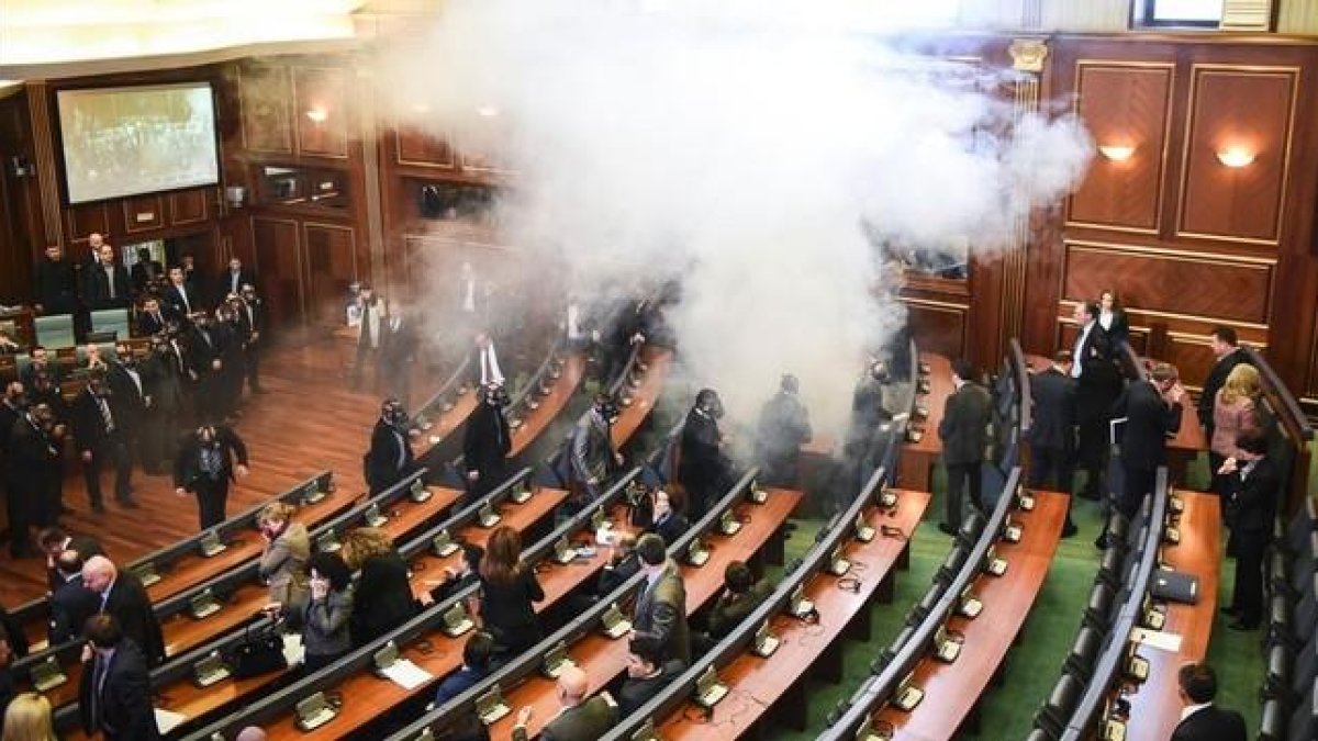 Diputados kosovares evacúan la sala tras el lanzamiento del gas, en la primera sesión parlamentaria del año, en Pristina.-AFP / ARMEND NIMANI