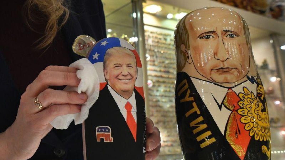La empleada de una tienda de 'souvenirs' de Moscú saca brillo a las matrioskas de Trump y Putin, a cuatro días de la investidura del primero como presidente de EEUU.-AFP / ALEXANDER NEMENOV