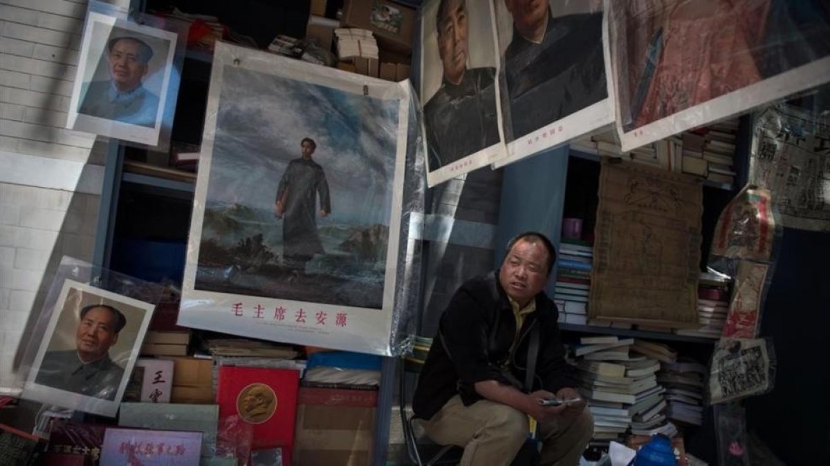 Un comerciante espera la llegada de clientes para vender imágenes y recuerdos de Mao Zedong.-AFP / NICOLAS ASFOURI