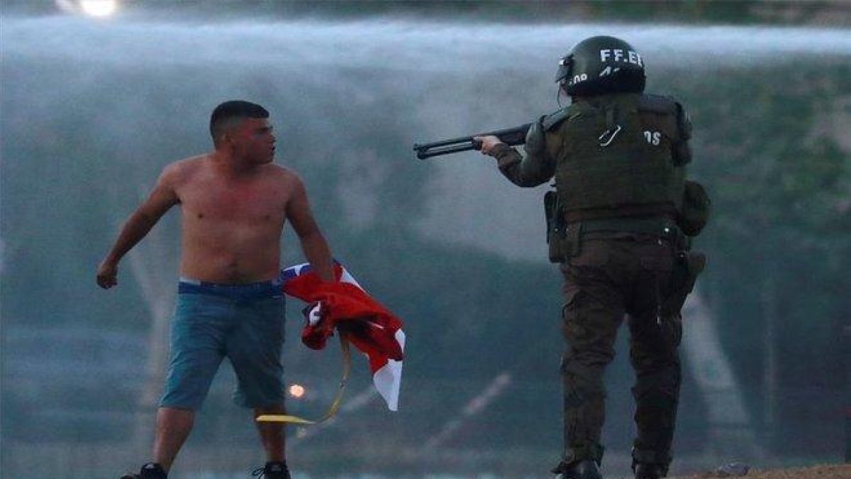 Un polícia en Chile apunta con su arma a un manifestante.-REUTERS