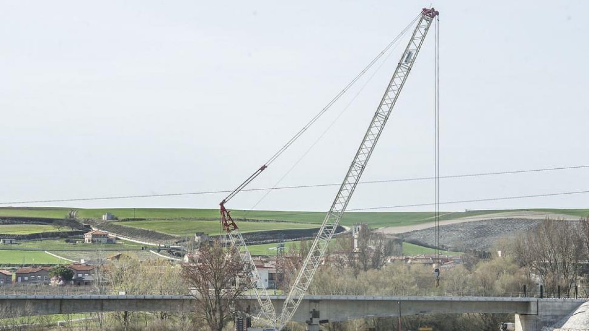 Una grúa de grandes dimensiones ha empezado a descolgar vías, barandillas y otros elementos del puente.-ISRAEL L. MURILLO