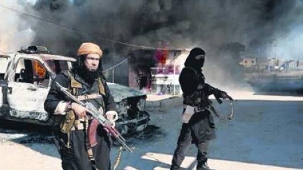 Dos miembros del ISIL, el pasado mes de enero, frente a un coche policial en llamas en Irak.-Foto: AP