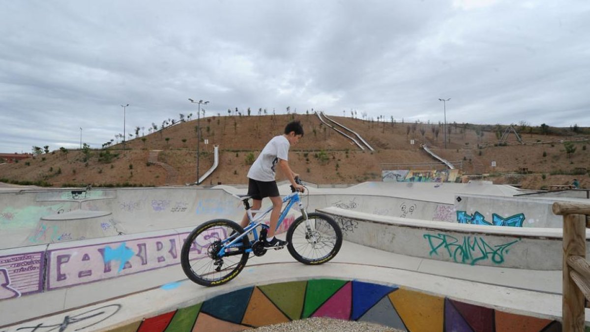 Un joven con una bicicleta en el parque de San Isidro. A partir de octubre se sembrarán las laderas.-ISRAEL L. MURILLO