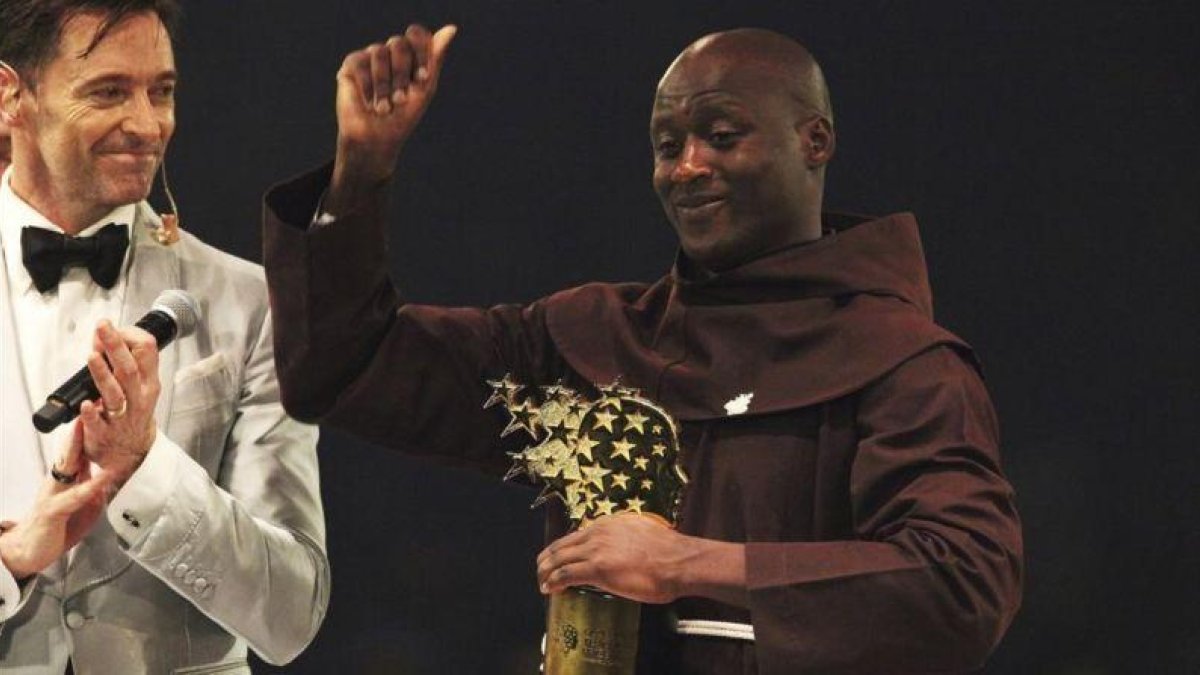 Peter Tabichi alza el trofeo que lo acredita como mejor profesor del mundo, junto al actor Hugh Jackman.-AFP