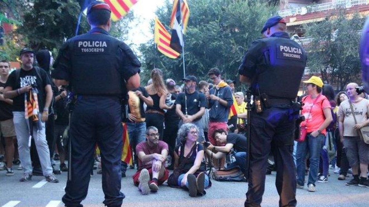 Dos agentes de los Mossos d’Esquadra, ante un grupo de manifestantes que organizó una sentada ante la sede de la Guardia Civil en la Travessera de Gràcia de Barcelona, el pasado 20 de septiembre.-MIQUEL CODOLAR ACN