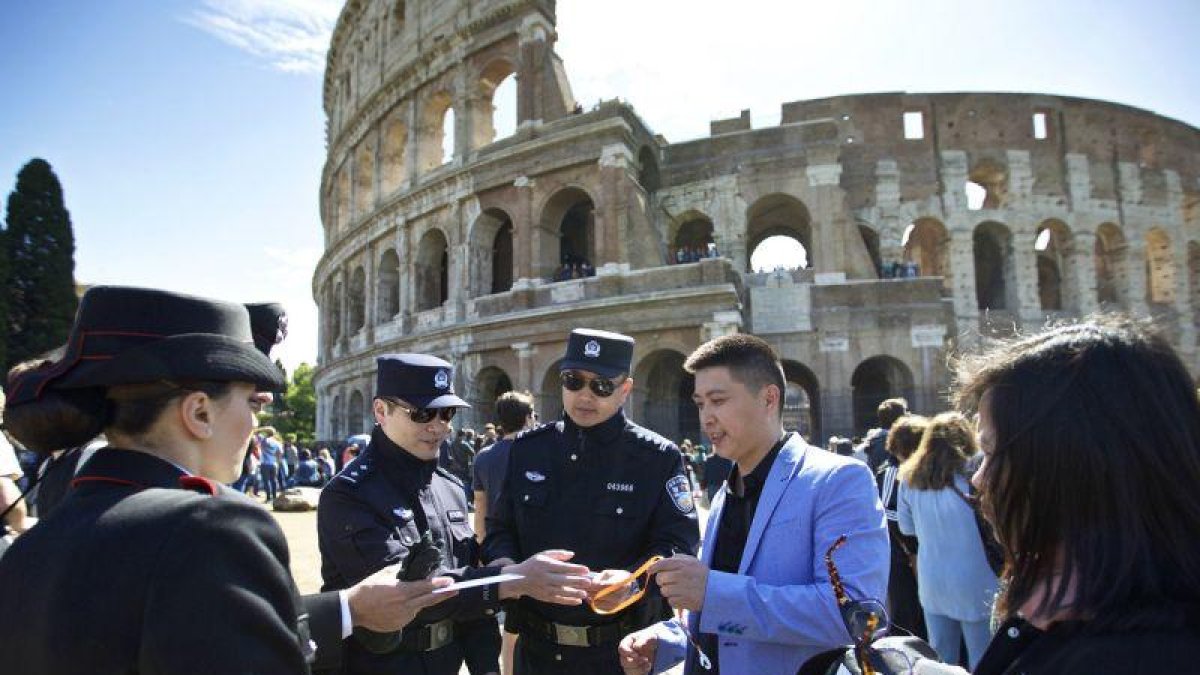Dos agentes chinos, junto a dos italianos, revisan la documentación de un grupo de turistas chinos, en el exterior del Coliseo, en Roma, este lunes.-AP / JIN YU