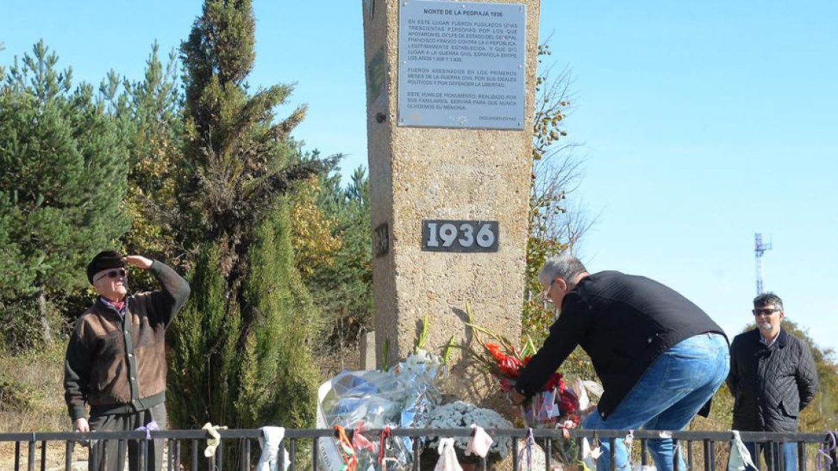 Varias personas depositan flores en el monumento del monte de La Pedraja.-ICAL