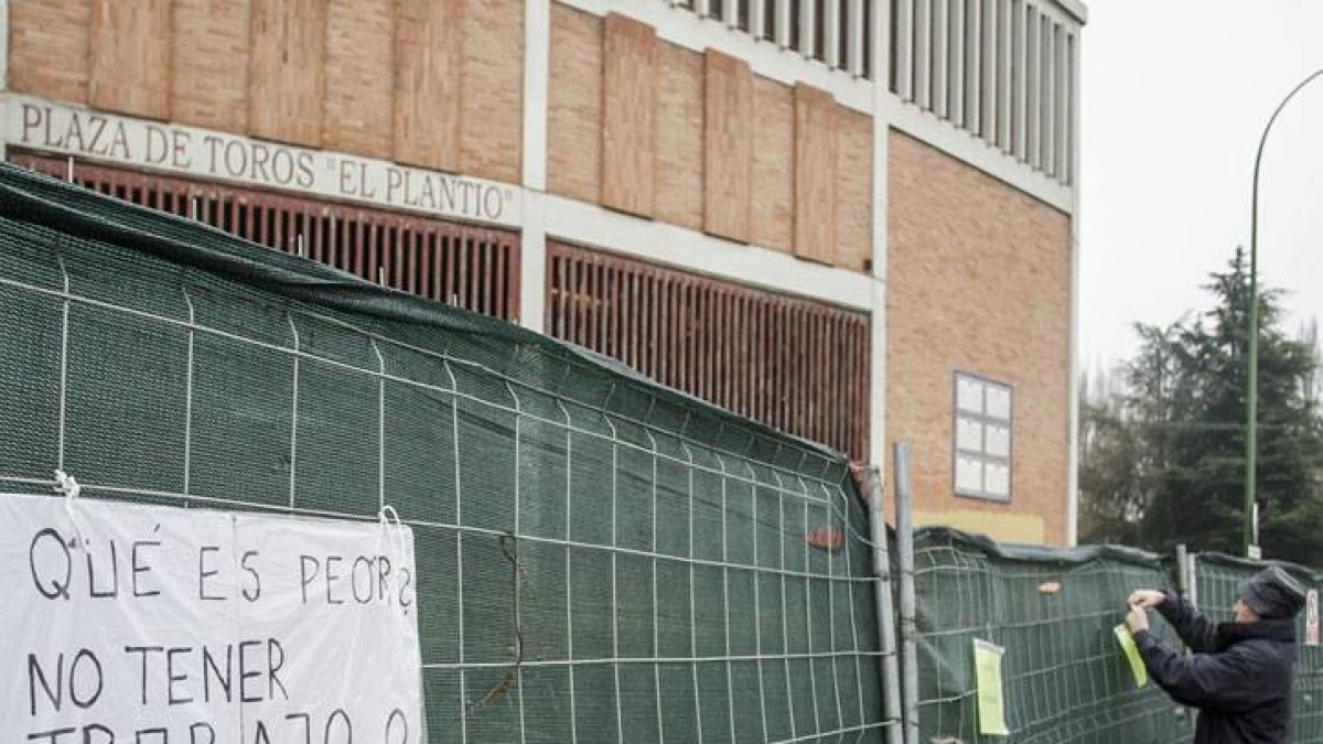 Un miebro de la asamblea coloca carteles en la valla que rodea el coso.-SANTI OTERO