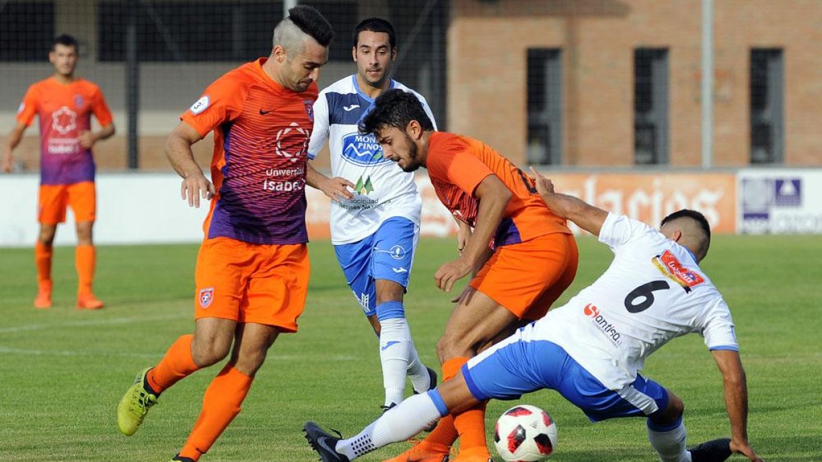 Torres y Manchado pugnan por un balón con un jugador del Almazán-Santi Otero