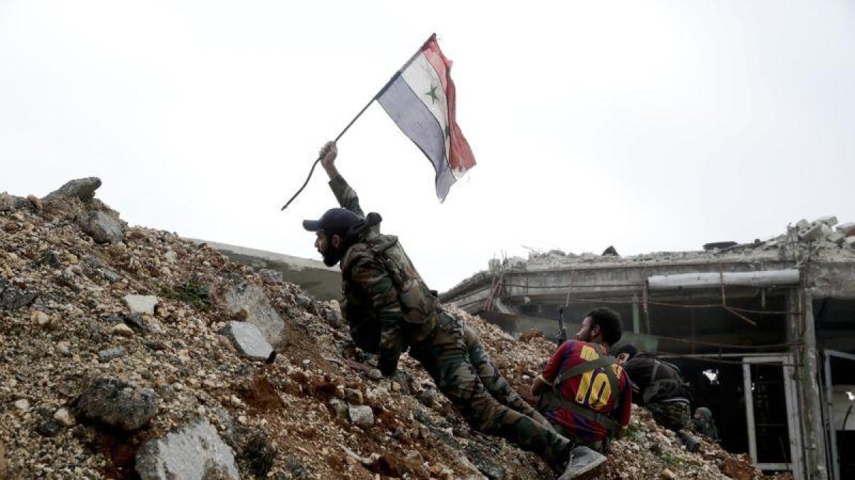 Un soldado del régimen sirio coloca una bandera en una zona de combate.-HASSÁN AMMAR / AP