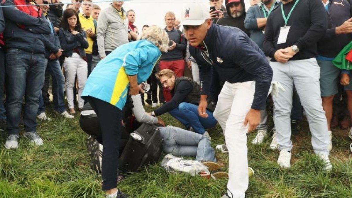 La espectadora de la Ryder, atendida en el suelo, tras un golpe de Brooks Koepka.-EL PERIÓDICO