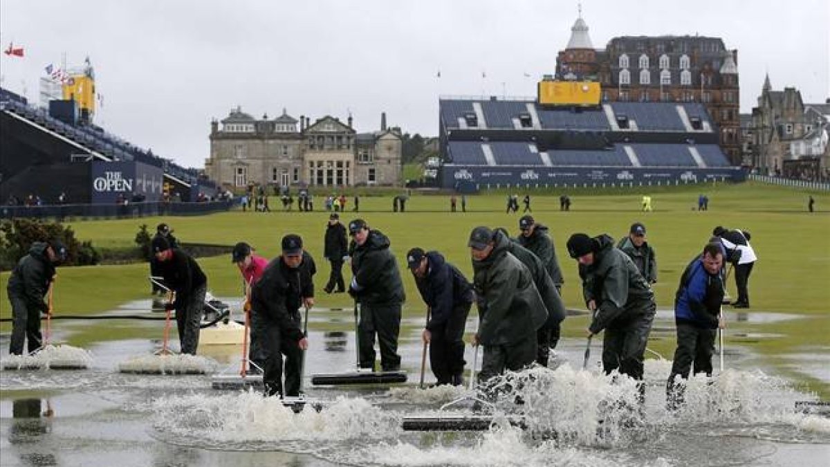 Operarios de Saint Andrews achican aguas para intentar que se reanude la jornada en el Abierto Británico.-Foto: AFP / ADRIAN DENNIS
