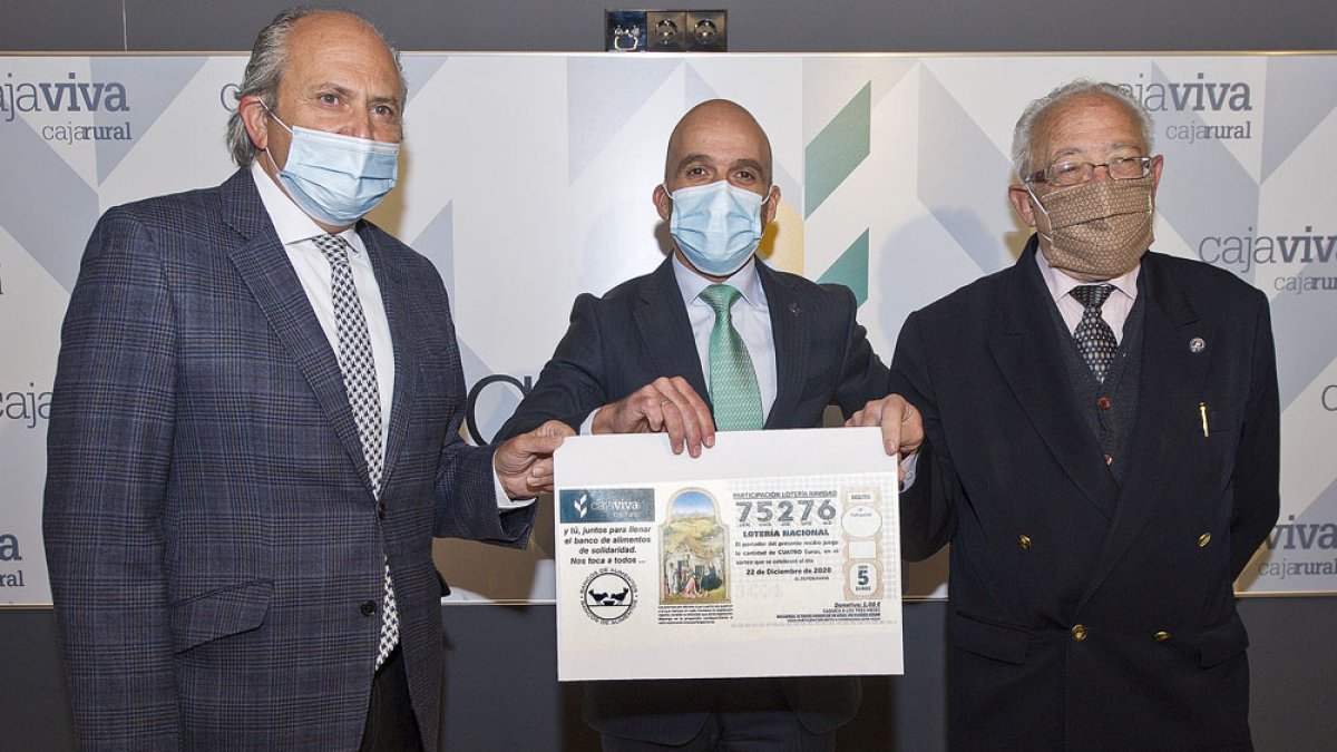 Julián Martínez, Javier Casado y Miguel Ángel López sostienen el número de Navidad que contribuye a la labor del Banco de Alimentos. ISRAEL L. MURILLO