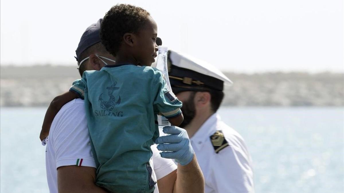 Un medico tiene en brazo un niño desembarcado del barco de la Guardia de Finanza en Pozzallo, Sicilia /-FRANCESCO RUTA (ANSA)
