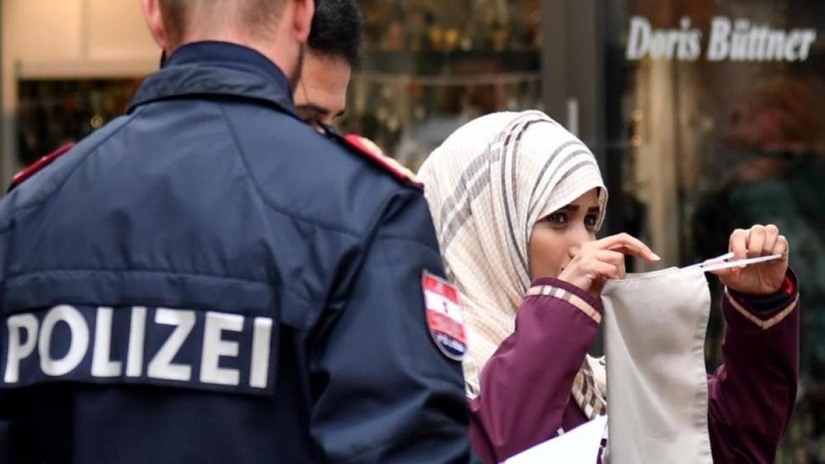 Un policía ordena a una mujer musulmana que se retire el velo en Austria.-AFP