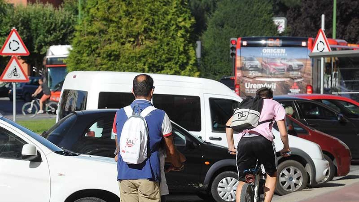 Un hombre circula en patinete y otro en bicicleta por el carril bici de la avenida de La Paz.