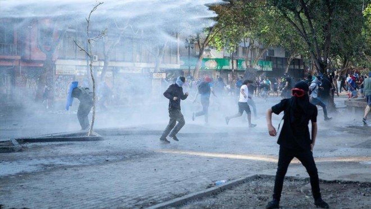 La policía lanza cañones de agua para dispersar a los manifestantes, el pasado sábado en Santiago.-PAULA ACUNZO (DPA)