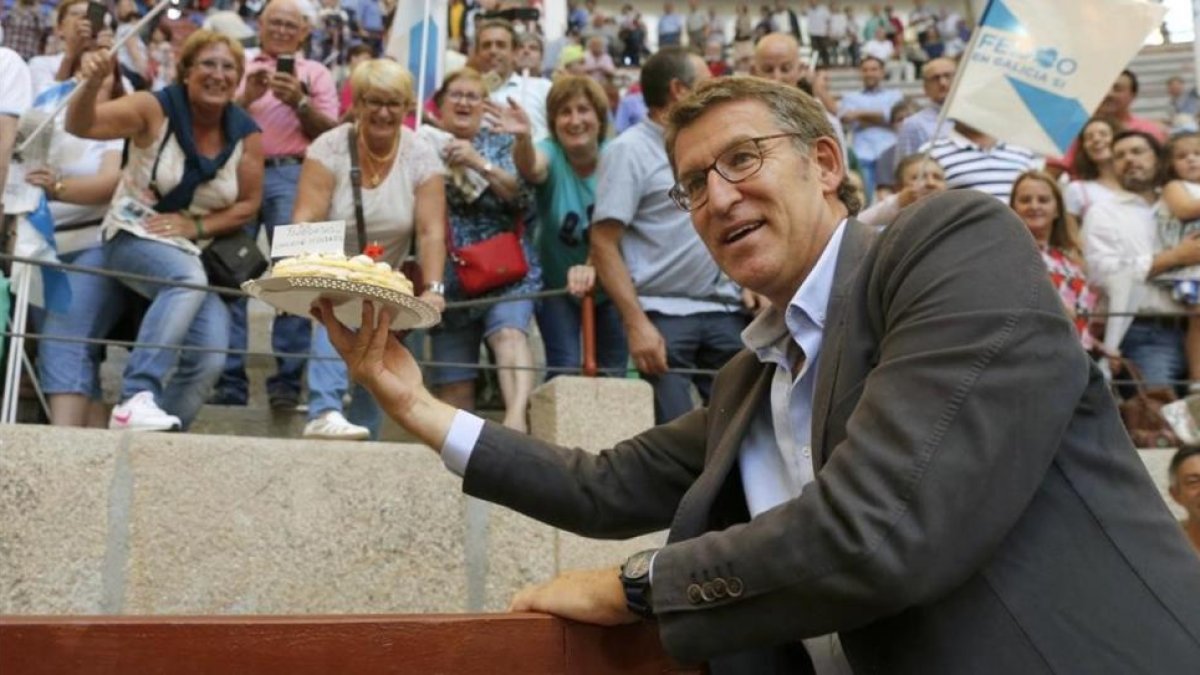 Alberto Núñez Feijóo saluda a varios simpatizantes que le regalaron una tarta por su cumpleaños, durante la campaña cara a las elecciones gallegas.-EFE