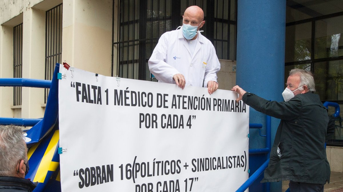 El doctor Juan José Jiménez coloca una pancarta reivindicativa junto al centro de salud. ISRAEL L. MURILLO