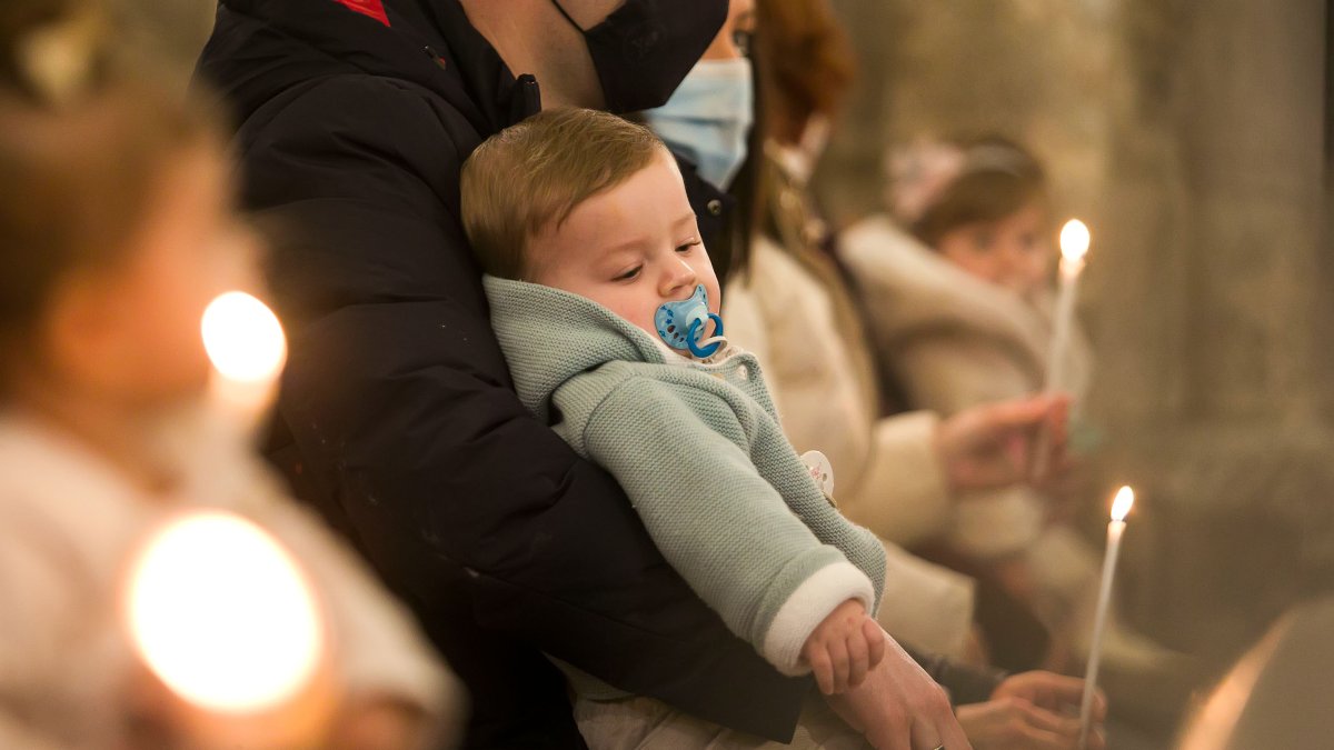 Un niño recostado sobre su padre durante la Misa de la Luz. TOMÁS ALONSO.