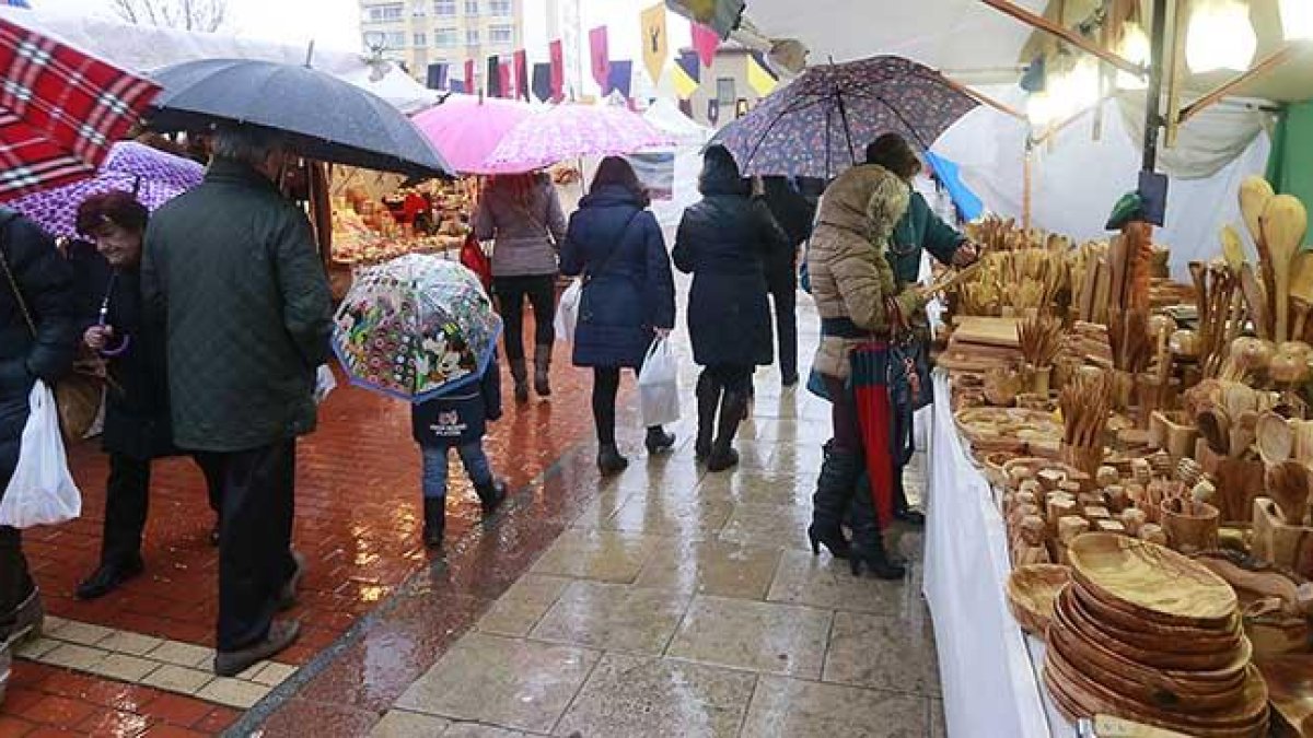 Buena parte de los comerciantes mantuvieron los puestos abiertos pese a la lluvia mientras que los compradores se refugiaban bajo los toldos o con paraguas.-R. OCHOA