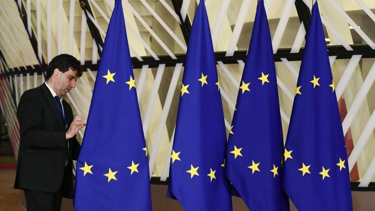 Un funcionario prepara las banderas de la Unión Europea antes del inicio de la cumbre, este domingo en Bruselas.-AFP