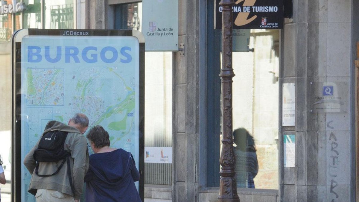 Dos personas miran el plano de la ciudad junto a las oficinas de turismo de la Junta en Burgos.