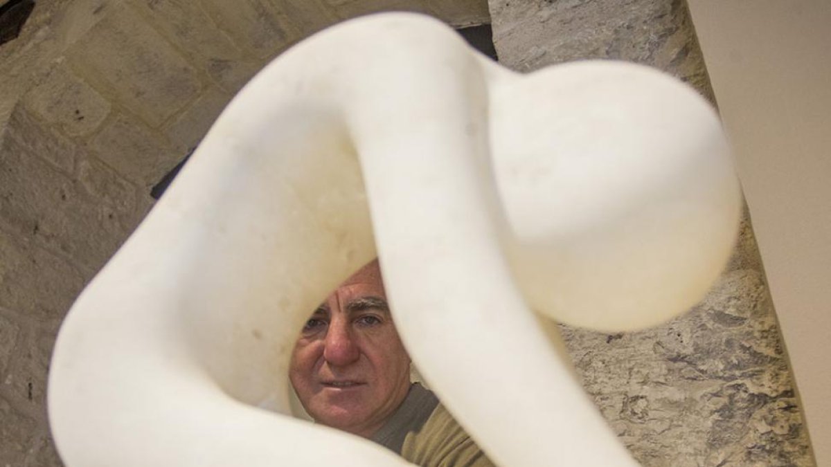 Julio Carazo se asoma por el aire que deja una escultura de alabastro titulada ‘De rodillas’.-Santi Otero