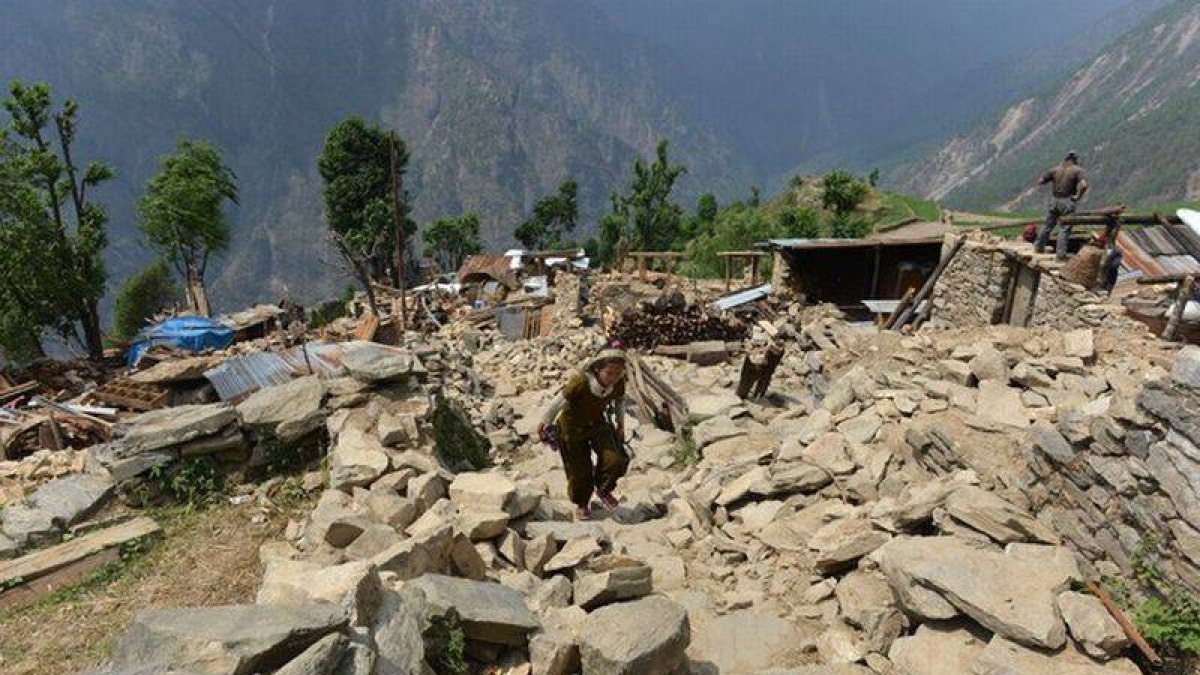 Nepalís caminan entre escombros de casas en la localidad de Ungul, a 60 kilómetros de Katmandú, el lunes.-Foto: AFP / PRAKASH MATHEMA