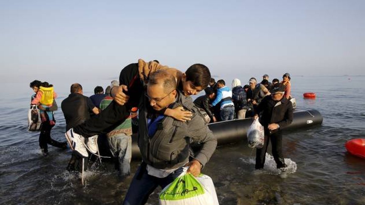 Un refugiado sirio llegado de Turquía carga con un niño en la isla griega de Kos.-Foto: REUTERS / YANNIS BEHRAKIS