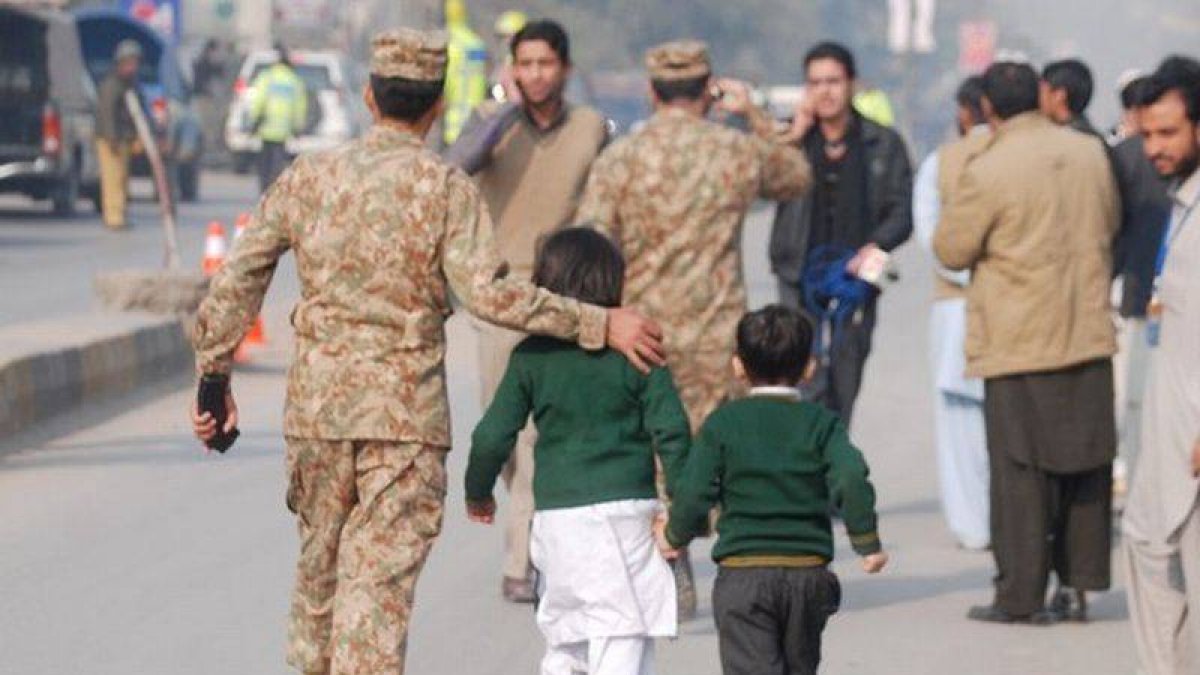 Un soldado paquistaní escolta a dos niños rescatados de la escuela que ha sufrido el ataque en Peshawar.-Foto: REUTERS / KHURAM PARVEZ