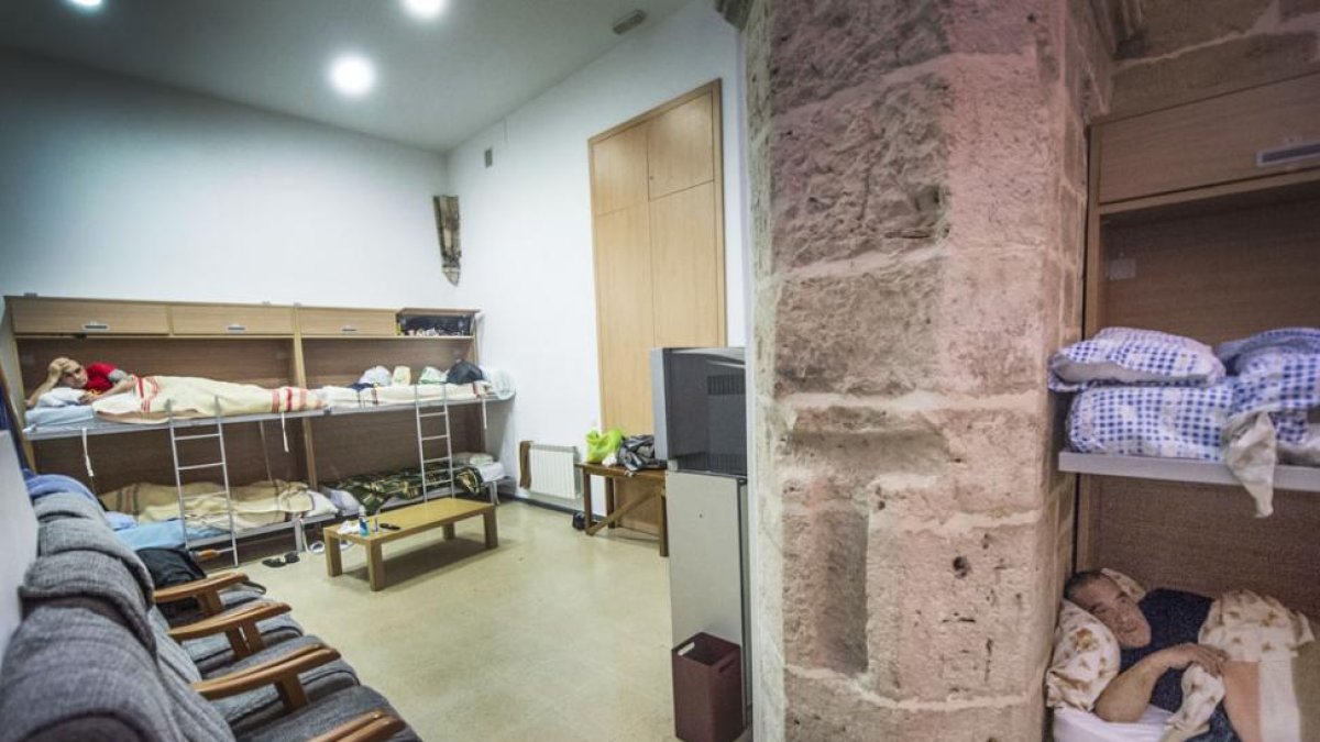 Dos personas descansan en las camas de la Unidad de Mínima Exigencia de Cáritas.-ISRAEL L. MURILLO