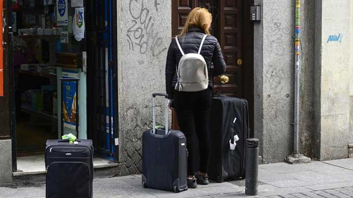 Una mujer accede a un portal de un piso turístico.