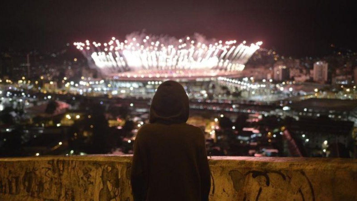Un niño observa desde el Morro da Mangueira los fuegos artificiales de Maracaná durante la ceremonia de clausura de los Juegos, este domingo.-EFE / FABIO TEIXEIRA