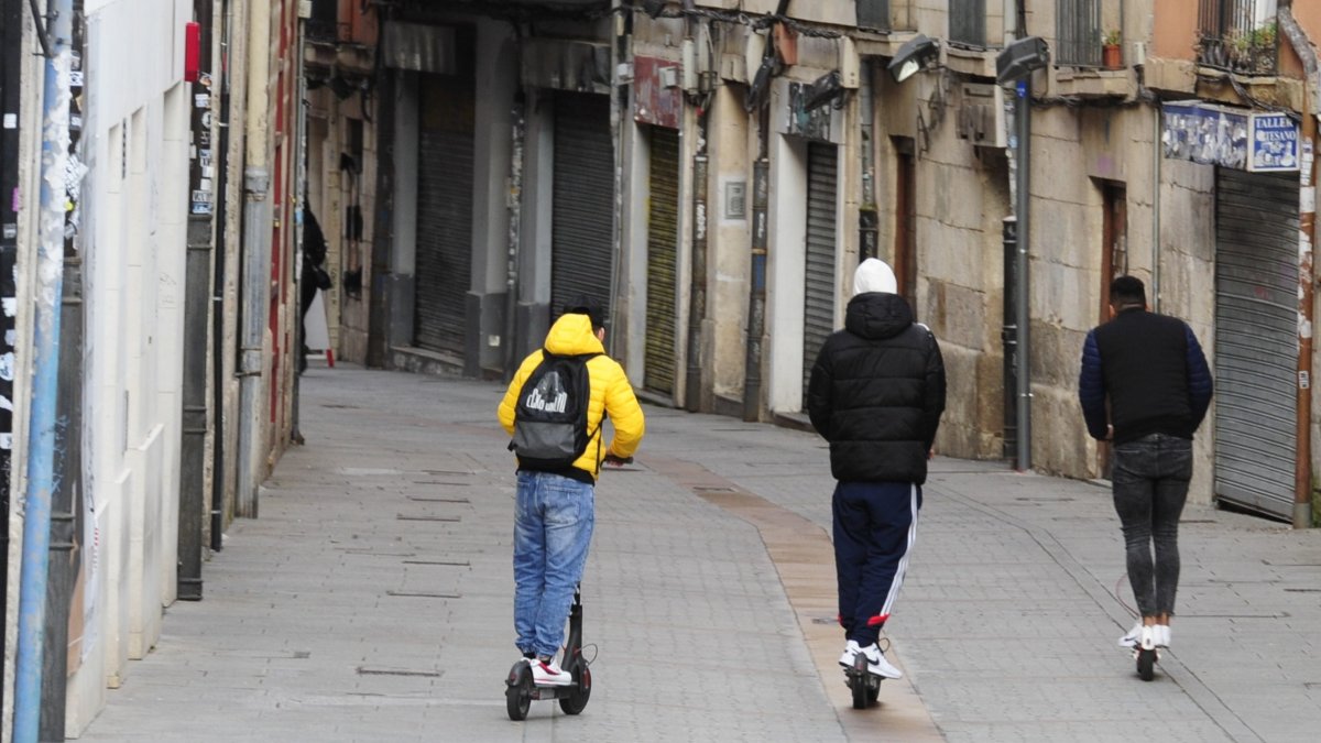 Tres jóvenes en patinete eléctrico por una céntrica calle de Burgos. RAÚL G. OCHOA