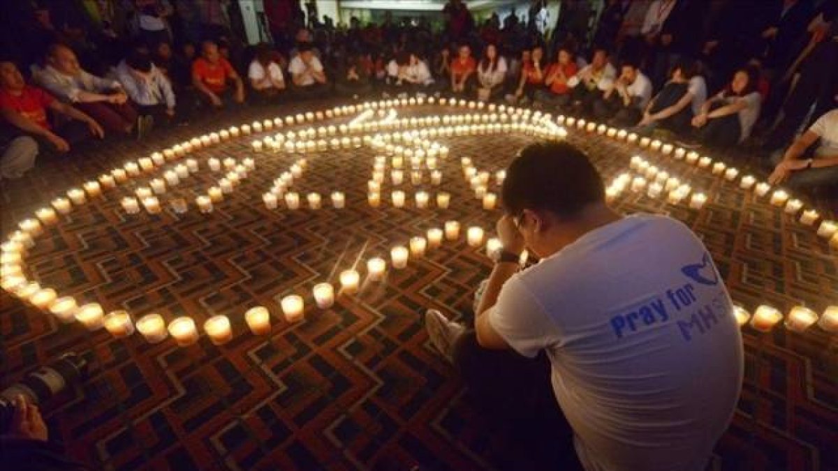 Familiares de pasajeros del vuelo Malaysia Airlines MH370 rezan en el Metro Park Hotel en Pekin.-Foto: AFP / WANG ZHAO