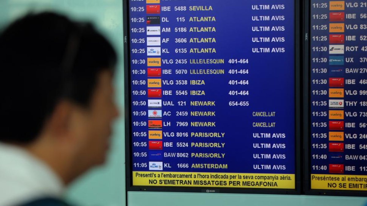Un viajero consulta la programación de vuelos en el aeropuerto de Barcelona.-DANNY CAMINAL