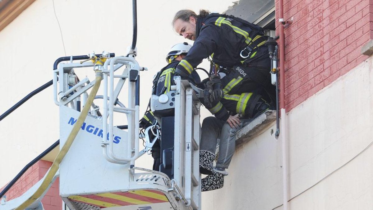 Uno de los bomberos accede a la ventana mientras otro conversa con el hombre.-ISRAEL L. MURILLO