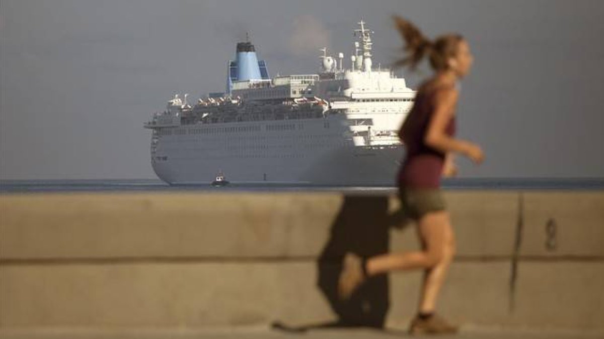 Una mujer corre por el Malecón mientras el crucero Thomson Dream llega a La Habana, el 19 de marzo.-Foto: AP / DESMOND BOYLAN