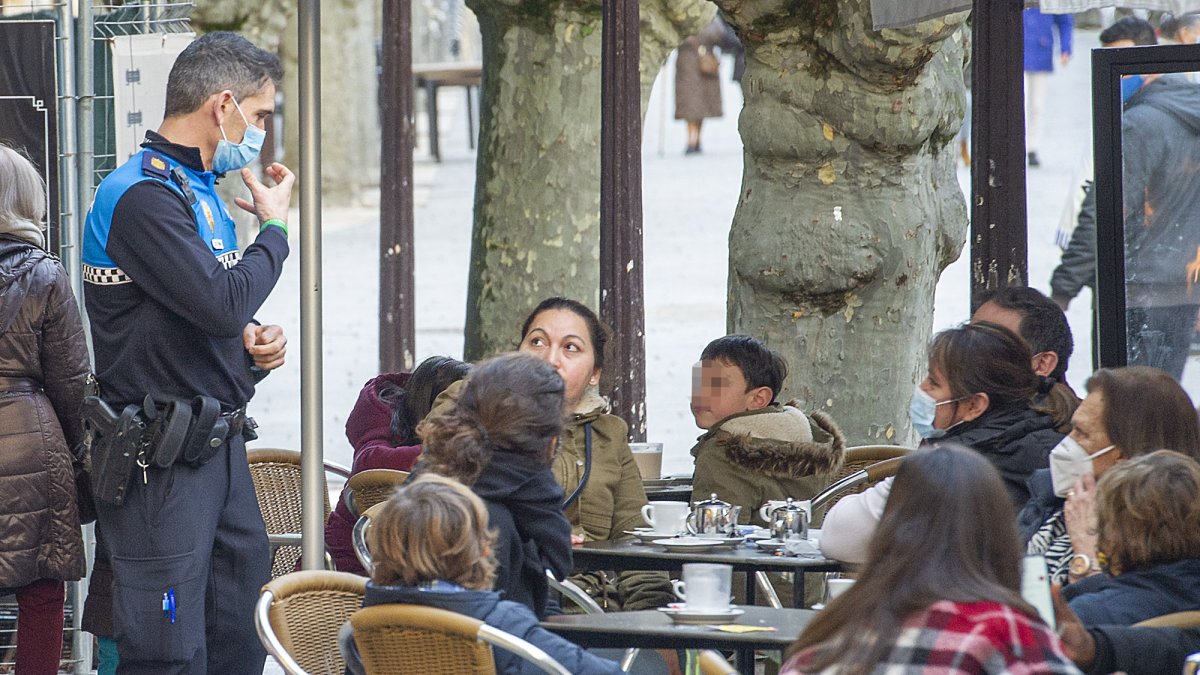 Un agente de Policía Local advierte sobre el uso de la mascarilla a los ciudadanos sentados en una terraza. ISRAEL L. MURILLO