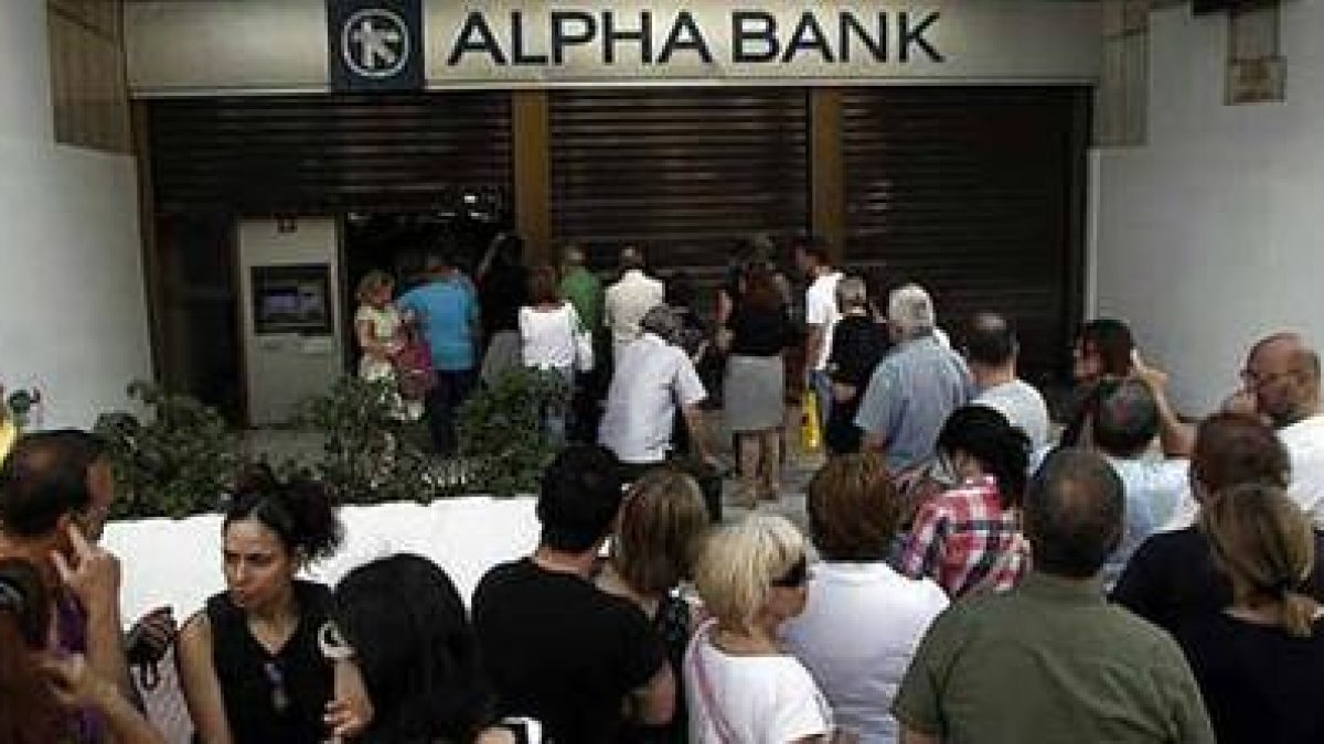 Decenas de personas hacen cola para sacar dinero de un banco en Atenas.-ALEXANDROS VLACHOS / EFE