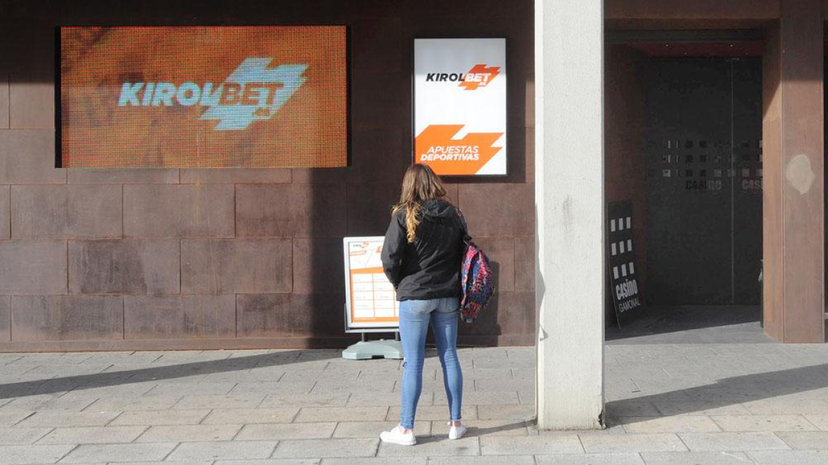 Un mujer oberva el cartel de una casa de apuestas.
