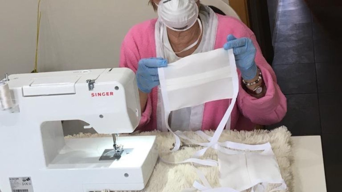 Una mujer confecciona una mascarilla con máquina de coser. ECB