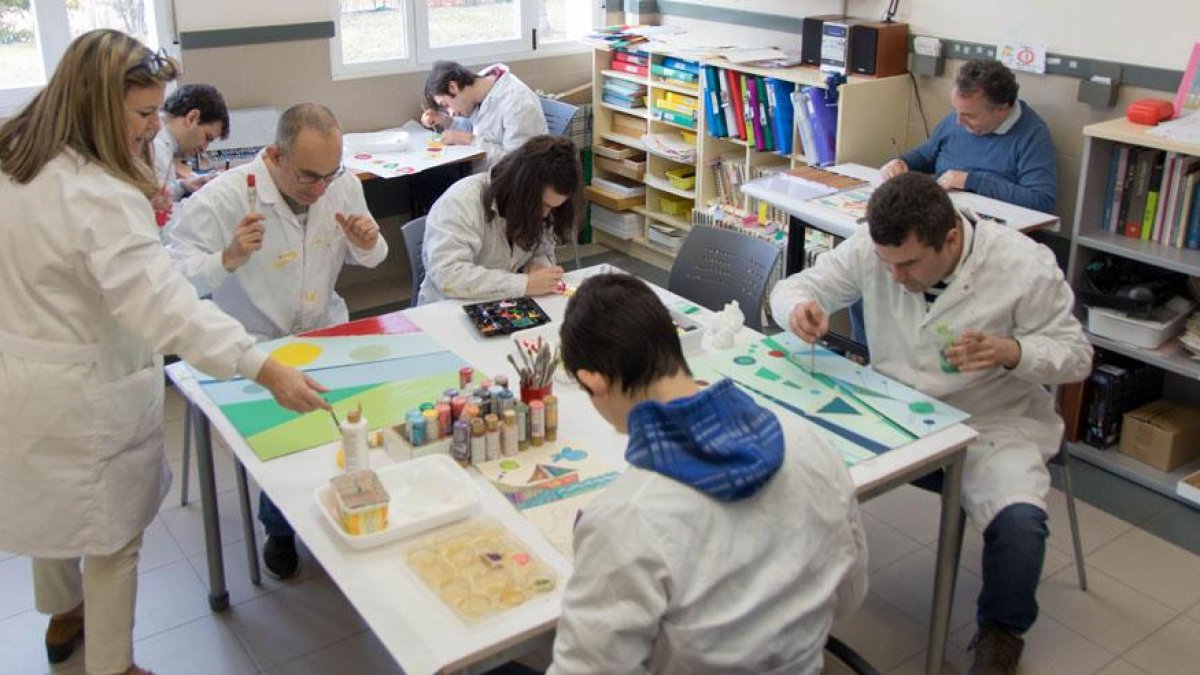 Diversos usuarios de la asociación realizan manualidades en una de sus aulas.-ECB