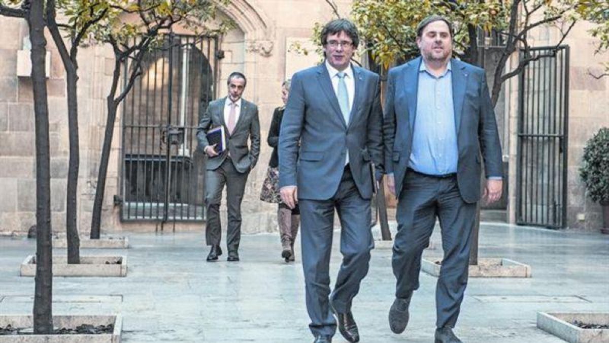 Carles Puigdemont y Oriol Junqueras caminan por el Pati dels Tarongers del Palau de la Generalitat, antes de una reunión de Govern.-FERRAN SENDRA