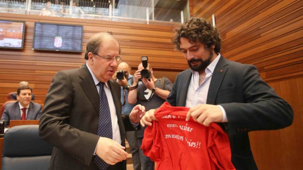 El portavoz de Izquierda Unida, José Sarrión, entrega una camiseta reivindicativa de los trabajadores de Itevelesa al candidato a la Junta de Castilla y León, Juan Vicente Herrera, en el debate de investidura del candidato a la Junta de Castilla y León-Ical