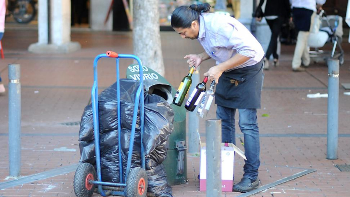 Un trabajador del sector hostelero recicla envases de vidrio.-ISRAEL L. MURILLO