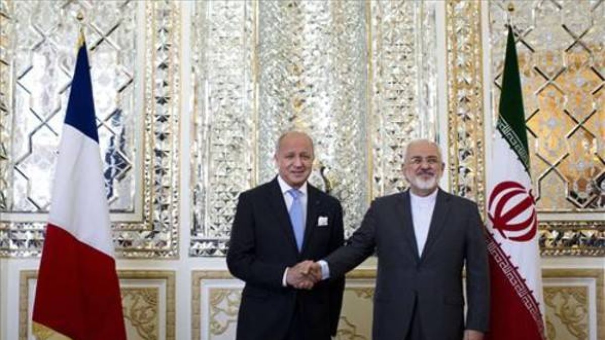 Los ministros de Exterior iraní y francés, Mohammad Javad Zarif (derecha) y Laurent Fabius (izquierda) se dan la mano antes de su reunión en Teherán este miércoles.-Foto: AFP/ ROUZ MEHRI